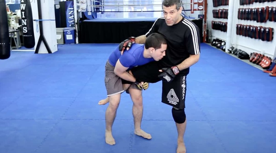 Grappler performing a single leg takedown in a BJJ training session.