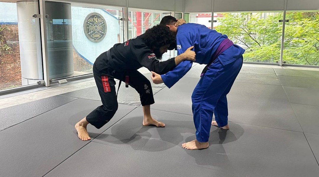 Wrestler executing a snap down to control opponent’s posture in BJJ.