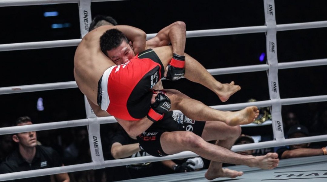 Wrestler demonstrating a double leg takedown technique in a grappling session.